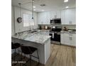 Modern kitchen with white cabinets, granite countertops, stainless steel appliances, and island with seating at 3614 N 48Th Dr, Phoenix, AZ 85031