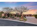 Stunning desert home with beautiful landscaping and three-car garage at sunset at 10712 E Greythorn Dr, Scottsdale, AZ 85262