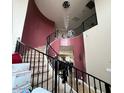 Elegant curved staircase with a chandelier and dark railing at 12321 W Florence St, Avondale, AZ 85323