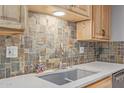 Modern kitchen sink with stone tile backsplash at 12411 N Cantata Ct, Sun City, AZ 85351