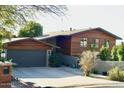 Modern home with wood siding, gray garage door, and landscaped yard at 2235 E Vista Ave, Phoenix, AZ 85020