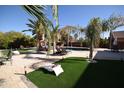 Expansive backyard featuring a patio with lounge chairs, a swing, artificial grass and desert landscaping at 31689 N Blackfoot Dr, San Tan Valley, AZ 85143