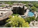Majestic aerial shot of circular home design featuring beautiful stone, clay tile roof and backyard pool area at 11105 E Tamarisk Way, Scottsdale, AZ 85262