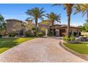 Paver driveway leads to an estate home with manicured grounds, palms and wrought iron entry gate at 6876 S Star Dr, Gilbert, AZ 85298