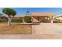 Tan single-story home with carport and nicely landscaped front yard at 13614 N Hawthorn Dr, Sun City, AZ 85351