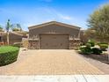 Two car attached garage with desert landscaping, stone accents, a tile roof, and a paved driveway at 6202 E Mckellips Rd # 83, Mesa, AZ 85215