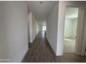 Hallway with wood-look flooring, neutral walls and access to rooms in a modern, well-lit home at 22852 E Lords Way, Queen Creek, AZ 85142