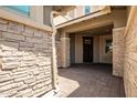 Stone-accented entryway with a covered porch and dark door at 13713 W Harvest Ave, Litchfield Park, AZ 85340