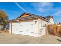 View of a two-car garage with a wooden gate nearby the structure at 21063 N 33Rd Ln, Phoenix, AZ 85027