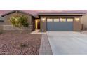 Front view of a house with gray garage doors and landscaping at 35350 W Marin Ave, Maricopa, AZ 85138