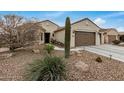 Tan house with a two-car garage and drought-tolerant landscaping at 3677 N Hudson Dr, Florence, AZ 85132