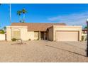 Tan house with a two-car garage and gravel driveway at 5448 W Shaw Butte Dr, Glendale, AZ 85304