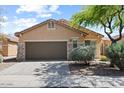 Tan house with a brown garage door and landscaping at 1719 W Owens Way, Anthem, AZ 85086