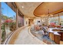 Open floor plan living area with stone flooring and curved walls of windows at 6520 E El Sendero Rd, Carefree, AZ 85377