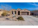 Tan house with a two-car garage and mature trees at 40950 W Bedford Dr, Maricopa, AZ 85138