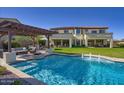 Beautiful backyard featuring a sparkling pool, lush greenery, covered patio, and a spacious lawn at 5528 E Windstone Trl, Cave Creek, AZ 85331