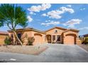Exterior view of a lovely tan house with a three car garage and desert landscaping at 12963 S 183Rd Ave, Goodyear, AZ 85338