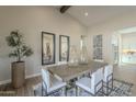 Elegant dining room with modern decor, a vaulted ceiling, and an adjacent kitchen area at 17380 W Carlisle Dr, Surprise, AZ 85388