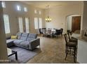 Open concept living room featuring a gray sectional sofa and a dining area with a chandelier at 8494 E Gilded Perch Dr, Scottsdale, AZ 85255