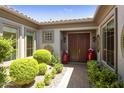 Elegant entryway with double doors, red planters, and lush greenery at 11175 N 121St Way, Scottsdale, AZ 85259