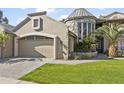 Tan two-story house with a stone turret, a large garage, and a manicured lawn at 10796 N 78Th St, Scottsdale, AZ 85260