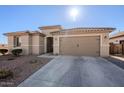 Exterior view of a tan house with a two-car garage and landscaping at 20121 W Lilac St, Buckeye, AZ 85326
