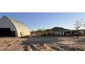 Exterior view of a property featuring a barn and a small house at 735 S Ruby Rd, Maricopa, AZ 85139