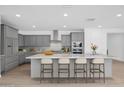 This open kitchen features gray cabinetry, stainless steel appliances, and a large island with seating at 17815 W Denton Ave, Litchfield Park, AZ 85340