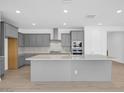 Modern kitchen features gray cabinets, stainless steel appliances, a large island, and a stylish backsplash at 17815 W Denton Ave, Litchfield Park, AZ 85340