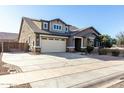 Two-story house with beige exterior, three-car garage, and driveway at 22235 E Munoz Ct, Queen Creek, AZ 85142