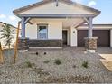 Inviting exterior featuring a stone facade, covered porch, and a well-maintained landscape at 4041 S 176Th Dr, Goodyear, AZ 85338