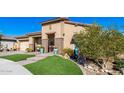 Tan two-story house with a three car garage and artificial turf at 21122 W Edgemont Ave, Buckeye, AZ 85396