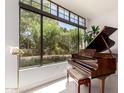 Elegant grand piano by large windows with lush outdoor views and abundant natural light at 8 E Biltmore Est # 117, Phoenix, AZ 85016