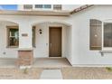 Welcoming front entrance featuring a covered porch with brick pillars and a stylish brown front door at 14670 W Sand Hills Rd, Surprise, AZ 85387