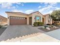 Front view of a tan house with a brown garage door and drought-tolerant landscaping at 26573 W Abraham Ln, Buckeye, AZ 85396
