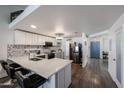 Well-lit kitchen boasts a center island, stainless steel appliances, and gray backsplash, leading to a blue accent door at 6352 W Campo Bello Dr, Glendale, AZ 85308