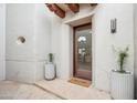 Charming home entrance with a glass door, stone flooring, potted plants, and stylish exterior lighting at 6411 S River Dr # 10, Tempe, AZ 85283
