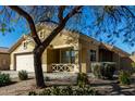 Tan house with a two-car garage, mature trees, and desert landscaping at 12740 S 175Th Dr, Goodyear, AZ 85338