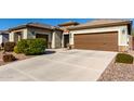 Two-car garage with long driveway and desert landscaping at 5640 W Victory Way, Florence, AZ 85132