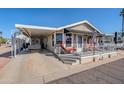 Mobile home with carport, covered porch and red patio furniture at 8865 E Baseline Rd # 1106, Mesa, AZ 85209