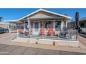 Front view of a beige mobile home with a covered porch and red chairs at 8865 E Baseline Rd # 1106, Mesa, AZ 85209
