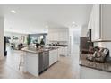 Open kitchen with white cabinets, granite island, and stainless steel appliances at 38130 W Bello Ln, Maricopa, AZ 85138