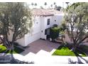 Beautiful two-story home features a red tile roof, lush trees and manicured lawn at 10113 E Topaz Dr, Scottsdale, AZ 85258