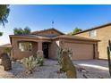 Front view of a tan house with cacti and a two-car garage at 1133 E Dust Devil Dr, San Tan Valley, AZ 85143