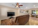 Living room with a brown couch, TV, and dining area at 1133 E Dust Devil Dr, San Tan Valley, AZ 85143