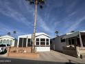 Front view of manufactured home with spacious driveway and palm trees at 2358 S Pomo Ave, Apache Junction, AZ 85119