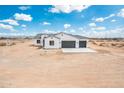 New construction white stucco home features a three-car garage and desert landscape at 25505 W Brookhart Way, Wittmann, AZ 85361