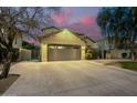 Two-story house with a three-car garage and well-manicured lawn at dusk at 4332 E Vallejo Ct, Gilbert, AZ 85298