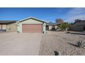 Light green single story home with a two-car garage and a rock front yard at 4938 W Michelle Dr, Glendale, AZ 85308