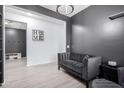 Small sitting area with gray walls, wood-look floors, and a dark couch at 17215 W Molly Ln, Surprise, AZ 85387